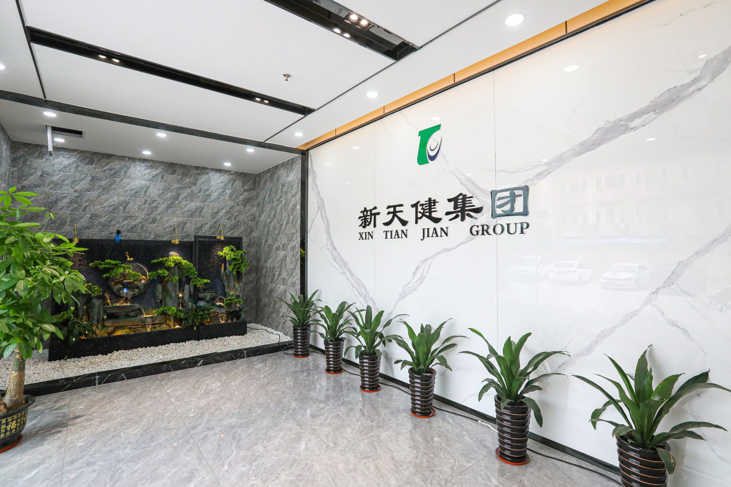 Entrance lobby of XTJ Precision Mfg with modern decor, marble walls, and potted plants.